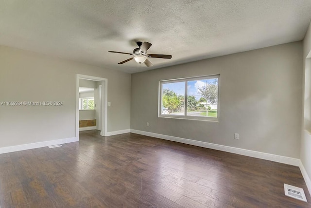 empty room with a textured ceiling, dark hardwood / wood-style flooring, and ceiling fan