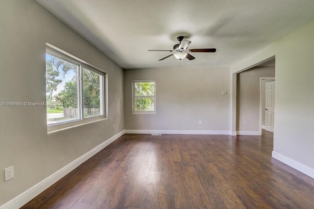 empty room with ceiling fan, dark hardwood / wood-style floors, and a textured ceiling