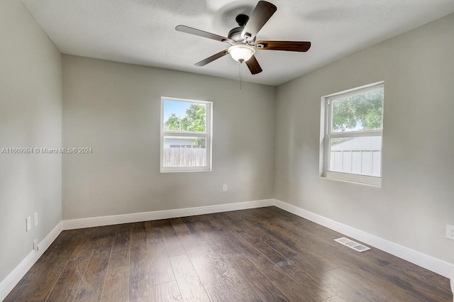 empty room featuring dark wood-type flooring, ceiling fan, a healthy amount of sunlight, and a textured ceiling