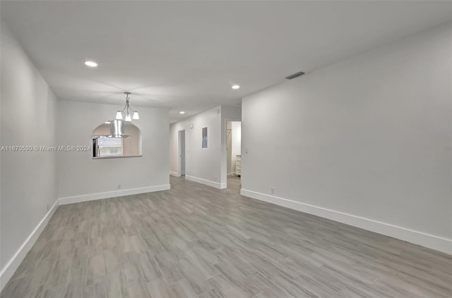 spare room featuring light hardwood / wood-style flooring and an inviting chandelier