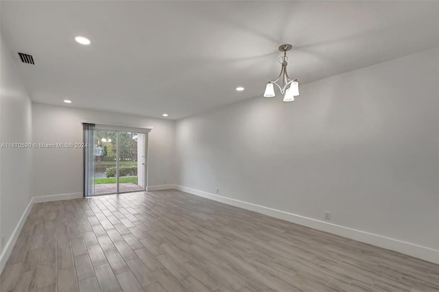 spare room with light wood-type flooring and an inviting chandelier