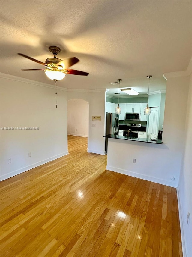 unfurnished living room with crown molding, ceiling fan, light hardwood / wood-style flooring, and a textured ceiling