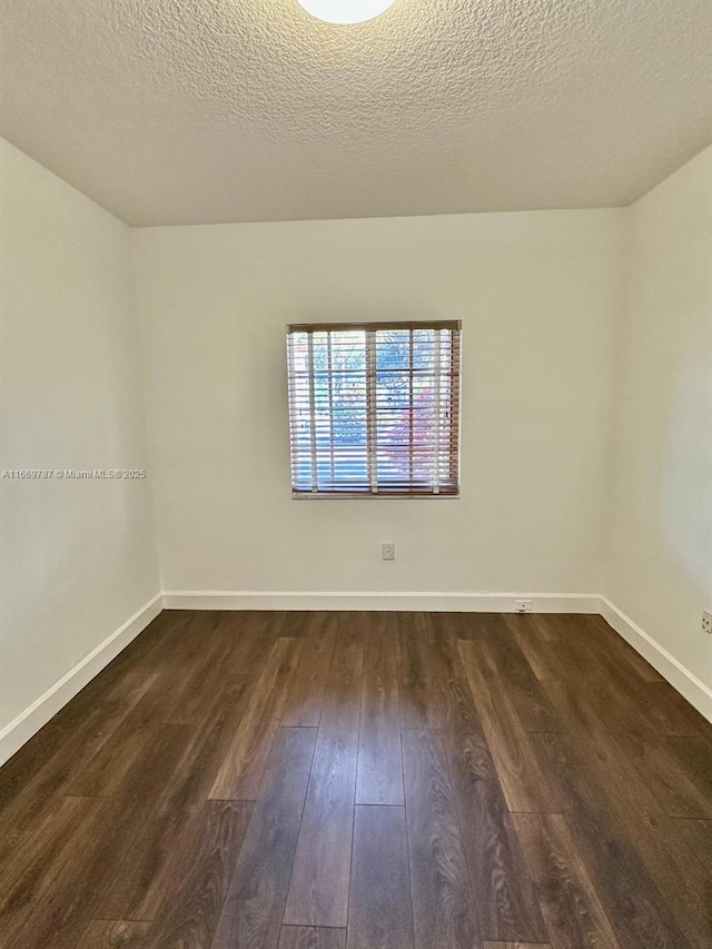 spare room featuring dark wood-type flooring and a textured ceiling