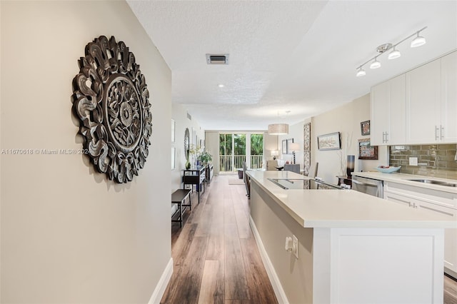 kitchen featuring a textured ceiling, light hardwood / wood-style floors, a kitchen island with sink, and white cabinets