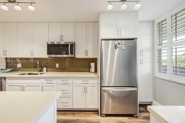 kitchen featuring white cabinetry, sink, light hardwood / wood-style flooring, and stainless steel appliances