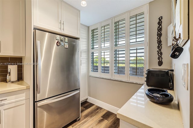 kitchen with white cabinets, stainless steel refrigerator, light wood-type flooring, and backsplash