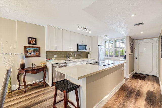 kitchen with light hardwood / wood-style flooring, white cabinets, appliances with stainless steel finishes, and sink