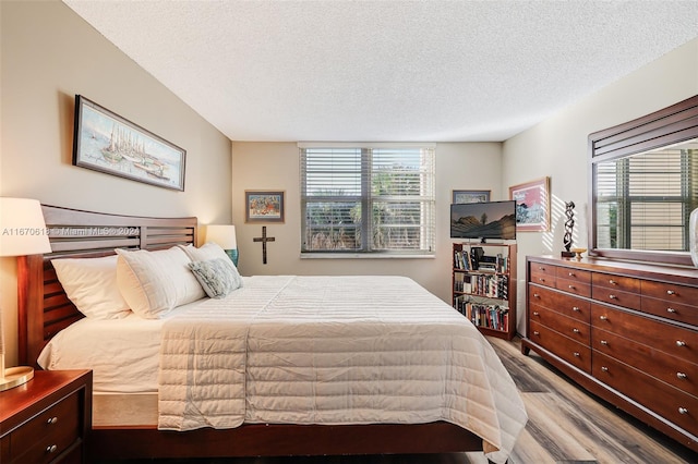 bedroom featuring wood-type flooring, a textured ceiling, and multiple windows