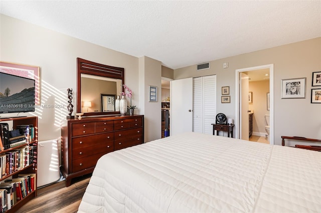 bedroom with ensuite bathroom, light hardwood / wood-style flooring, a closet, and a textured ceiling