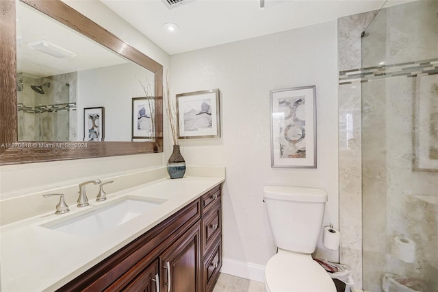 bathroom with tiled shower, vanity, and toilet