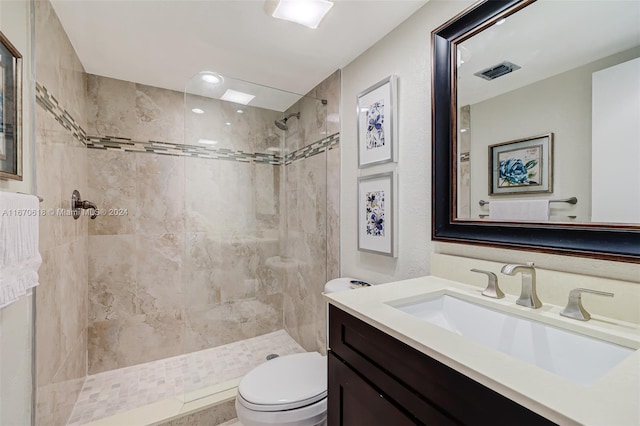 bathroom featuring toilet, vanity, and tiled shower