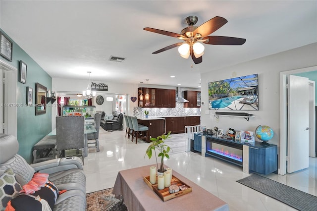 living room with ceiling fan with notable chandelier and light tile patterned floors