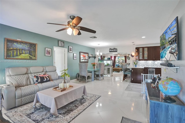 tiled living room with ceiling fan with notable chandelier