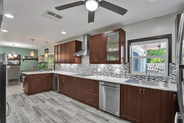 kitchen featuring wall chimney exhaust hood, sink, decorative light fixtures, dishwasher, and kitchen peninsula