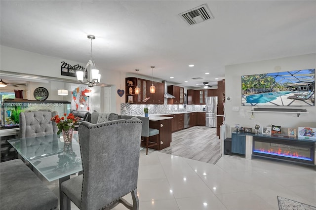 dining space featuring light tile patterned floors and ceiling fan with notable chandelier