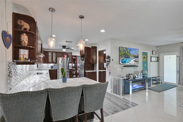 kitchen with ceiling fan, stainless steel fridge with ice dispenser, kitchen peninsula, decorative light fixtures, and light tile patterned flooring