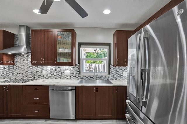 kitchen with ceiling fan, sink, stainless steel appliances, wall chimney range hood, and tasteful backsplash