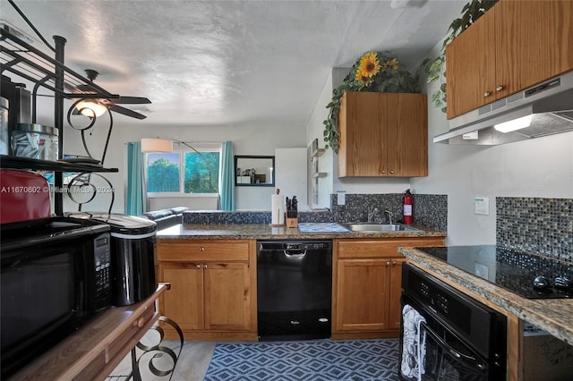 kitchen featuring decorative backsplash, dark stone counters, ceiling fan, sink, and black appliances