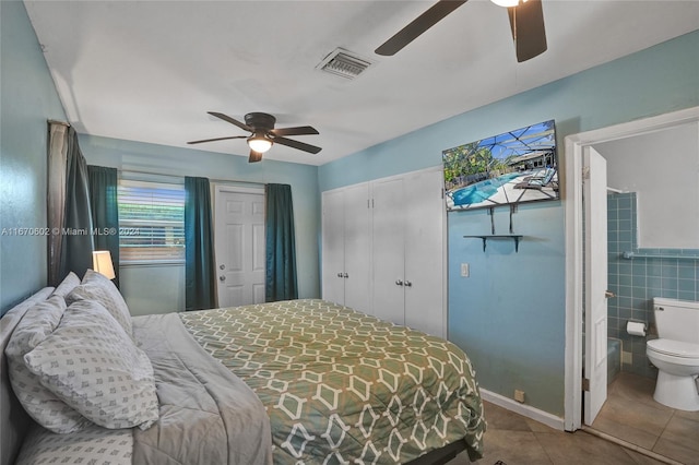 tiled bedroom with ceiling fan, ensuite bathroom, and tile walls