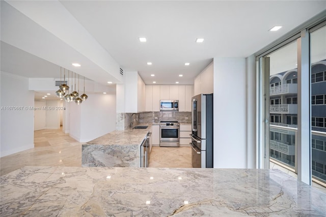 kitchen with sink, stainless steel appliances, tasteful backsplash, decorative light fixtures, and white cabinets