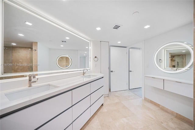 bathroom featuring tile patterned flooring, a tile shower, and vanity