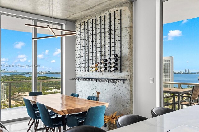 dining area with a notable chandelier, floor to ceiling windows, and a water view