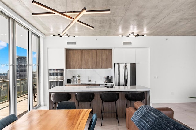 kitchen featuring white cabinets, stainless steel appliances, a kitchen breakfast bar, and a healthy amount of sunlight