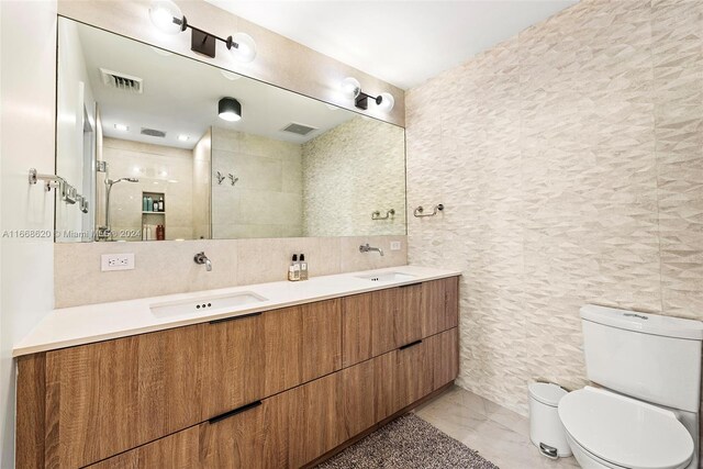 bathroom featuring vanity, a shower, toilet, and tile walls