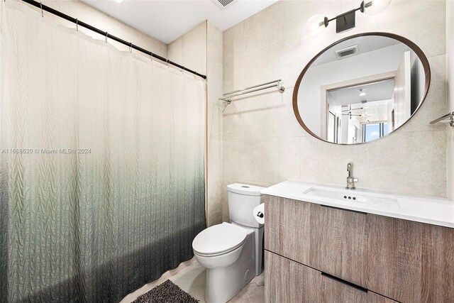 bathroom featuring tile walls, vanity, toilet, and a shower with curtain