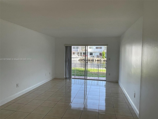 tiled spare room featuring a water view