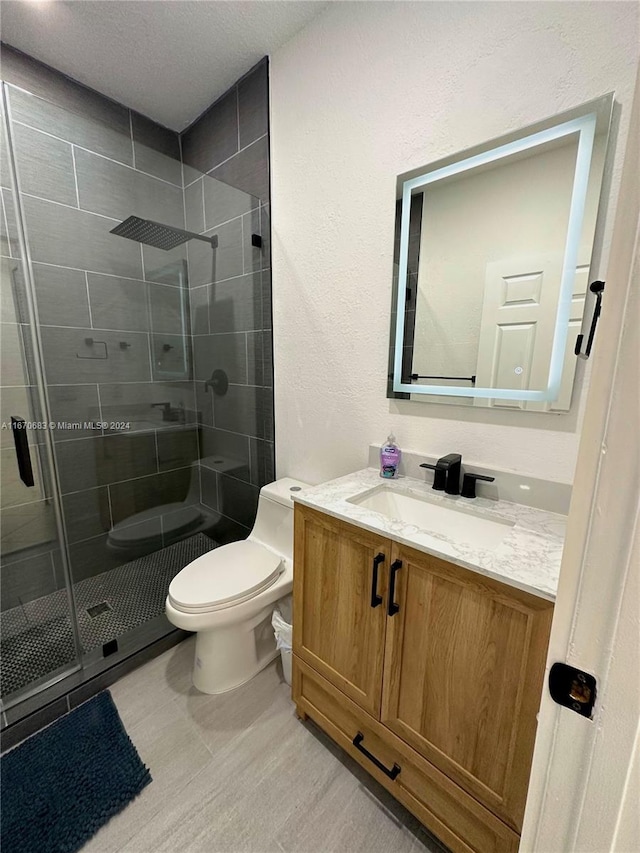 bathroom featuring vanity, wood-type flooring, a textured ceiling, a shower with shower door, and toilet