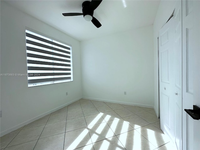 unfurnished bedroom with light tile patterned floors, ceiling fan, and a closet