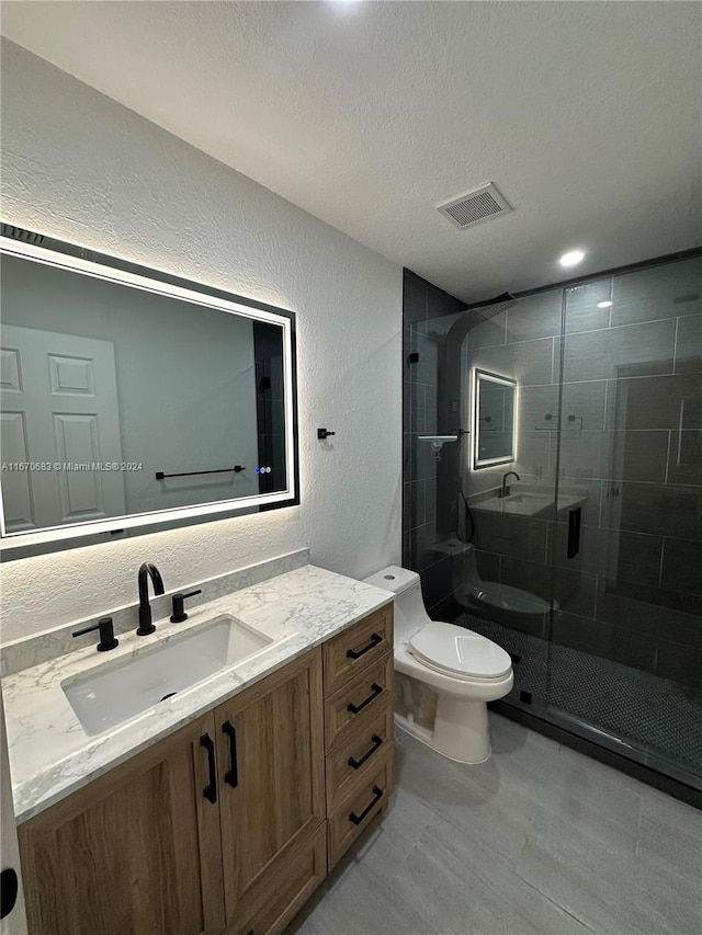 bathroom with vanity, a textured ceiling, toilet, and a shower with door