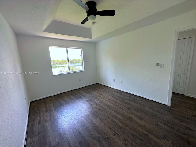 unfurnished room featuring ceiling fan, a raised ceiling, and dark hardwood / wood-style floors