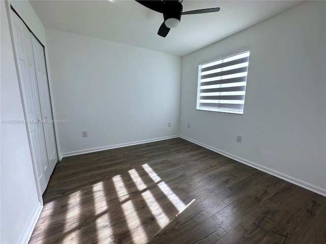 unfurnished bedroom with dark wood-type flooring, ceiling fan, and a closet