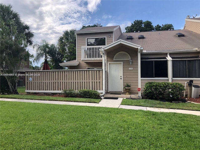 view of front of house featuring a balcony and a front lawn