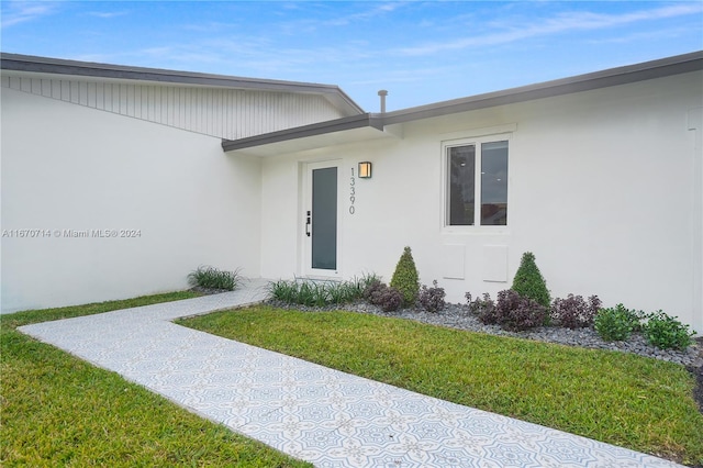 view of exterior entry with a yard