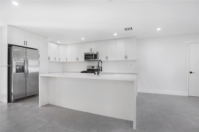 kitchen with white cabinetry, sink, stainless steel appliances, a center island with sink, and light tile patterned flooring