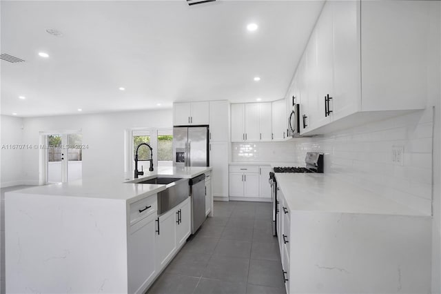 kitchen with a kitchen island with sink, sink, white cabinets, and stainless steel appliances