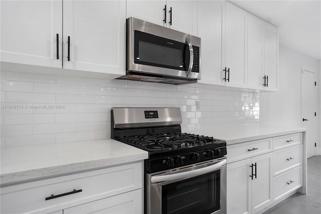 kitchen with light stone countertops, white cabinetry, stainless steel appliances, and tasteful backsplash