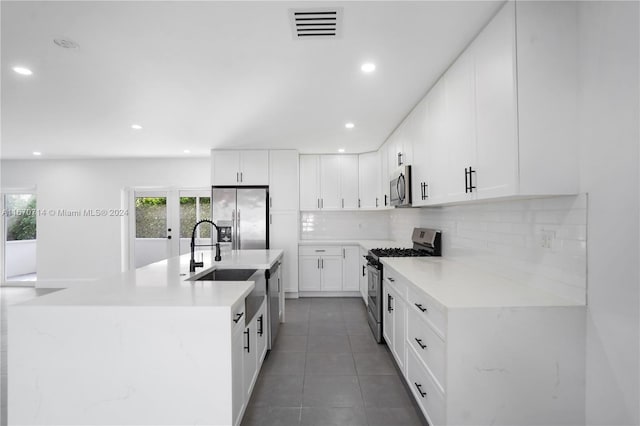 kitchen with white cabinets, sink, an island with sink, tasteful backsplash, and stainless steel appliances