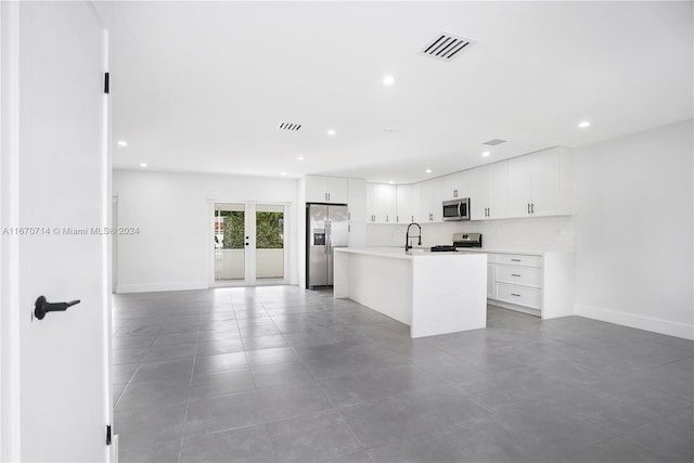 kitchen featuring backsplash, a center island with sink, white cabinets, sink, and appliances with stainless steel finishes