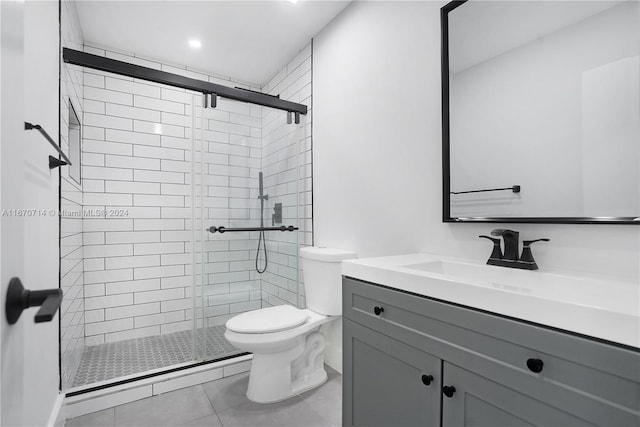 bathroom featuring tile patterned floors, a shower with door, vanity, and toilet