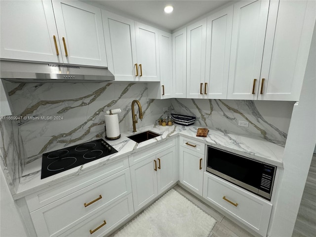 kitchen featuring black electric stovetop, tasteful backsplash, sink, and white cabinets