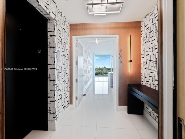 hall with wooden walls and light tile patterned floors