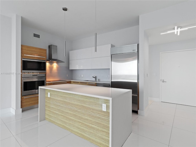 kitchen featuring wall chimney exhaust hood, black appliances, a center island, white cabinetry, and hanging light fixtures