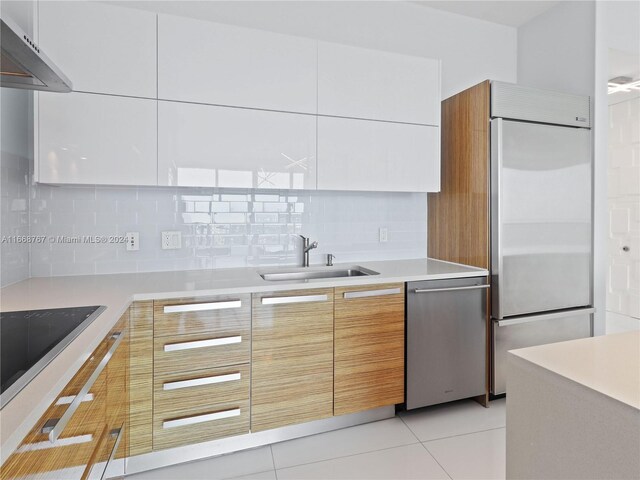 kitchen with backsplash, stainless steel appliances, white cabinetry, and sink