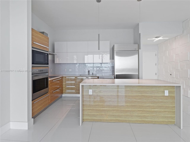 kitchen featuring white cabinetry, hanging light fixtures, tasteful backsplash, built in appliances, and light tile patterned flooring