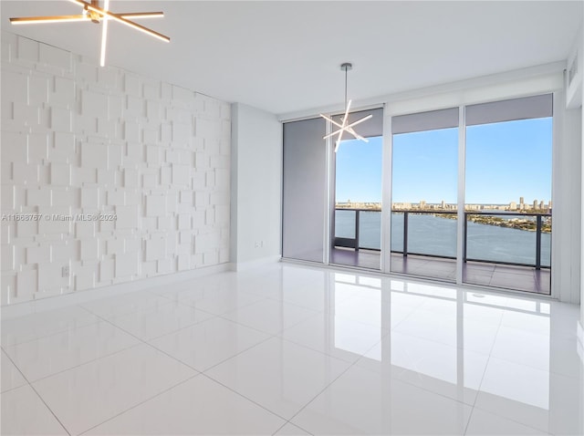 unfurnished room featuring light tile patterned floors, a water view, and an inviting chandelier