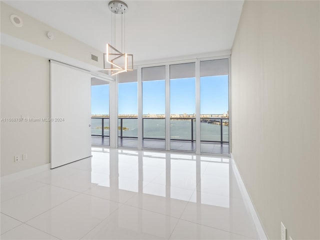 unfurnished room featuring a water view, floor to ceiling windows, and light tile patterned floors